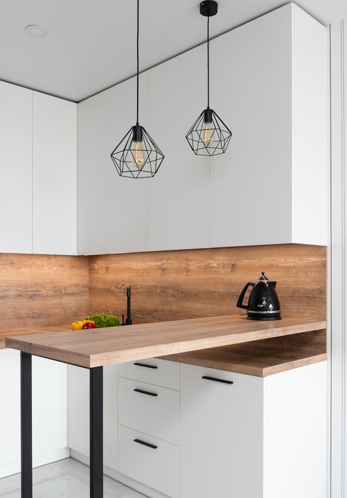 about-us-02 Interior of modern white kitchen with timber table and metal geometrical glowing lamps